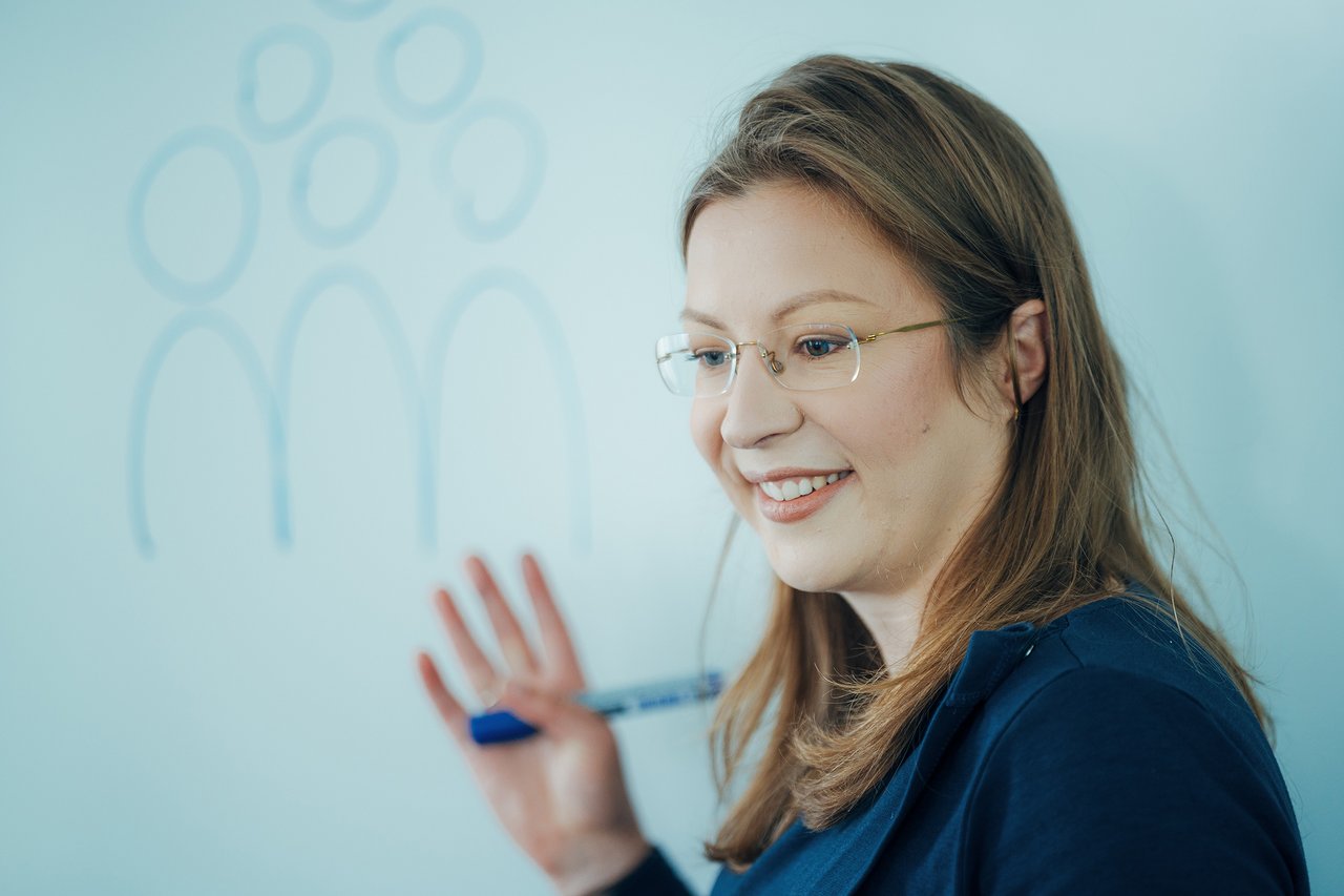 Mitarbeiterin von HMS wirbt im Austausch vor einem Whiteboard für usere Initiativen